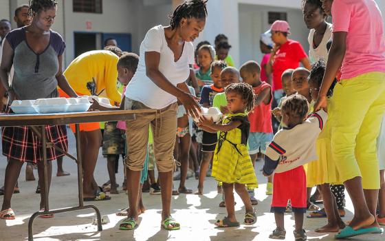 Haitian children who escaped violence in Cité Soleil line up to receive food at a school in Port-au-Prince July 22, 2022. An upsurge in gang-related violence has shut access to health services across some urban areas in Haiti, leaving one in 20 children living in Cité Soleil, a violence-ravaged commune, at risk of dying from severe acute malnutrition, UNICEF warned. (CNS/Reuters/Ralph Tedy Erol)