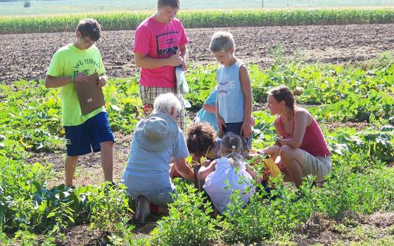 Sr. Kathleen "Kay" Fernholz , a School Sister of Notre Dame, works in the garden with children at Earthrise Farm in Madison, Minnesota. (Courtesy of Kathleen Fernholz)