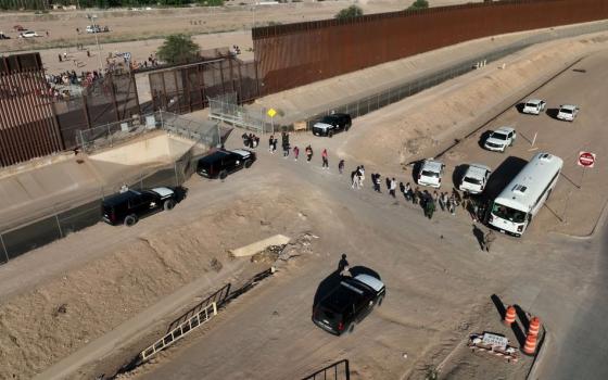 Migrants line up to board a U.S. Customs and Border Protection bus after crossing the U.S.-Mexico border before the lifting of Title 42 near El Paso, Texas, May 11. (OSV News/Reuters/Julio Cesar Chavez)