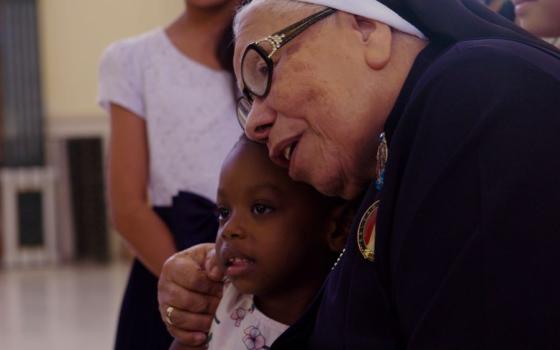 Sr. Maria Rosa Leggol hugs a child in this scene from the film "With This Light," premiering in select theaters this summer.