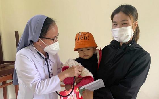 Filles de Marie Immaculée Sr. Rosa Vo Thi Hien examines the baby of Van Kieu ethnic Ho Thi Xoa May 26 in Cam Lo district. (GSR photo/Joachim Pham)