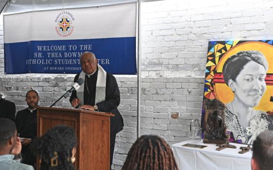 Cardinal Wilton Gregory speaks at a lecturn next to a painted portrait of Sister Thea Bowman