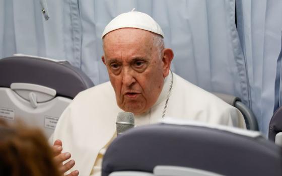 Pope holds microphone during press conference on plane