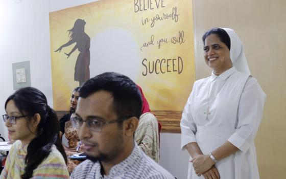 Nun dressed in white stands near a poster that says, "Believe in yourself and you will succeed."