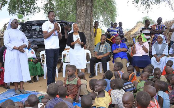 From left: Sr. Mary Lilly Driciru, a Missionary Sister of Mary Mother of the Church and coordinator of the Africa Faith and Justice Network women's empowerment program in Uganda; a translator; and Notre Dame de Namur Sr. Eucharia Madueke address a rural community in Karamoja, Uganda, about child trafficking to Kampala, Uganda. (Courtesy of Eucharia Madueke)