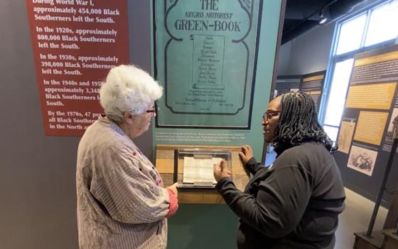 Sr. Barbara Pfarr (left), a School Sister of Notre Dame, visits America's Black Holocaust Museum in Milwaukee on Sept. 29. She listens to docent Brenda Jackson explain that in the 1930 edition of the Green Book, only two cities in Wisconsin, Fond du Lac and Oshkosh, offered services to the Black community. (Courtesy of Barbara Pfarr)