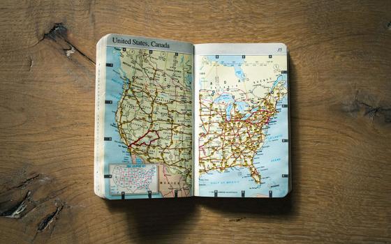 An atlas lies open to a map of the United States (Unsplash/Domino)