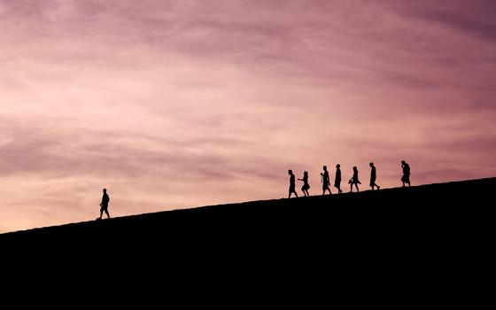 A wide shot shows one person walking far ahead of a group of others, in this photo illustration.