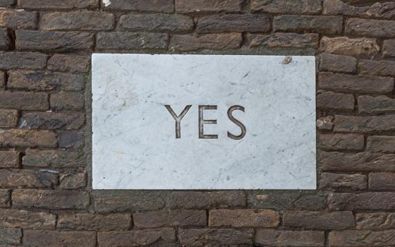 "Yes" carved in a white plaque on a brick wall (Unsplash/Florian Schmetz)