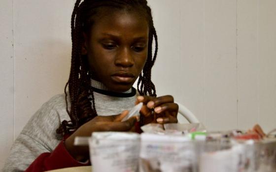 Aminata makes tiny ornaments for a constructio paper Christmas tree Dec. 13, 2023, in the apartment she and her sister share in Chicago. (GSR photo/Dan Stockman)