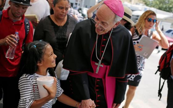 Bishop holds a little girls hand as they walk among a group.