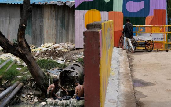 Laborers wash their clothes in sewage water under a bridge in New Delhi, India, on Aug. 24.