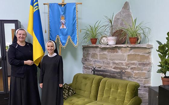 Sr. Yeronima Rybakova, left, holds part of a Ukrainian flag next to Sr. Josifa Lesnichenko, who teaches English at the school that the Sisters of the Order of St. Basil the Great operate in Ivano-Frankivsk, Ukraine, Sept. 3, 2022. (CNS/Rhina Guidos)