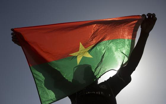 A protester holds up a Burkina Faso flag in Ouagadougou, the capital of Burkina Faso, in 2014. At least 15 people were killed in an attack by gunmen on Catholics gathered for Sunday Mass in a Burkina Faso village Feb. 25, 2024. (OSV News/Reuters/Joe Penney)