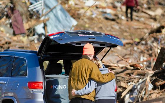 A couple hugs standing next to a truck looking at destruction from a tornado (Unsplash/Chandler Cruttenden)