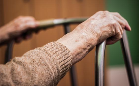 An elderly person's hands rest on a walker (Dreamstime/Sanjagrujic)