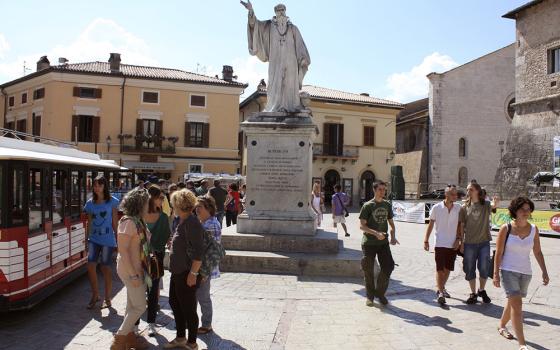Tourists and townspeople surround a statue of St. Benedict Aug. 14, 2013, in the small Italian town of Norcia. (CNS/Henry Daggett)