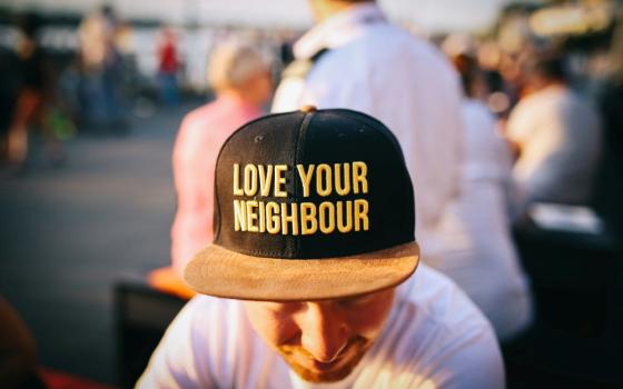 front of baseball cap reads "Love your neighbor."