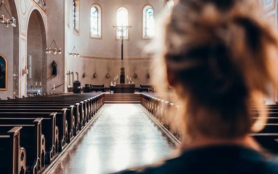 Woman enters an empty church (Unsplash/Thomas Vitali)