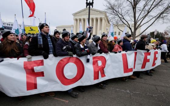 People carry a banner past the U.S. Supreme Court while participating in the 49th annual March for Life in Washington Jan. 21, 2022. 