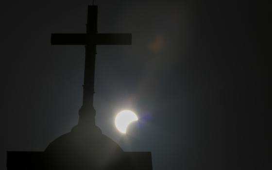 Cross silhouetted against eclipsing sun