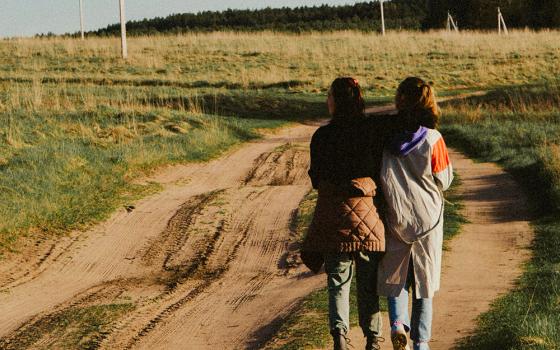 Two friends walking along a dirt road (Unsplash/Klara Kulikova)