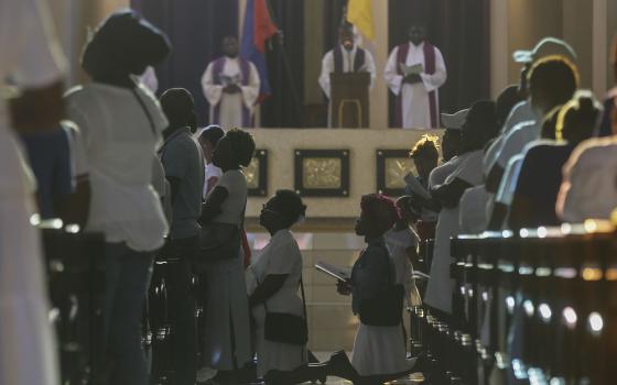 People kneel at pews and in aisle of church