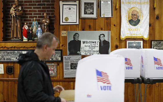 Religious artwork and vintage photographs adorn a wall behind a voter as he completes his ballot at a polling place inside St. Leo the Great Roman Catholic Church, Nov. 6, 2018, in Baltimore's Little Italy neighborhood. Evangelical support of Trump held strong in 2020 but shifted with nonreligious voters, according to analysts. (AP photo/Patrick Semansky)