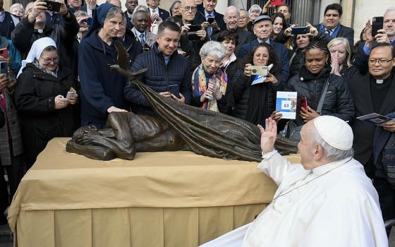 ope Francis waves to members of the Vincentian religious orders and lay communities Nov. 9, 2022, after blessing Canadian artist Timothy Schmalz' sculpture "Sheltering." The statue, which features a dove laying a blanket over a homeless person, was to be used in conjunction with a Vincentian project to build homes for some 10,000 people in 160 countries. (CNS/Vatican Media)
