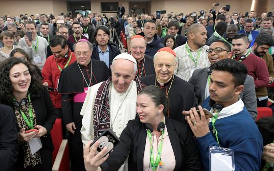 Pope Francis poses for a selfie during a pre-synod gathering of youth delegates, including NCR contributor Nicole M. Perone, far left, at the Pontifical International Maria Mater Ecclesiae College in Rome on March 19, 2018. The meeting was in preparation for the Synod of Bishops on young people, the faith and vocational discernment this October at the Vatican. (CNS/Vatican Media)
