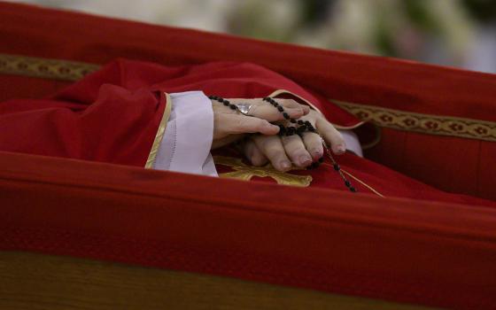 The hands of Pope Francis, holding a rosary, are seen as he lies at rest in his coffin in the chapel of his residence