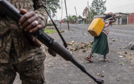 A child carrying water walks past militia forces fighting M23 rebels in Sake, Democratic Republic of the Congo, on Aug. 31, 2024. (AP/Moses Sawasawa)