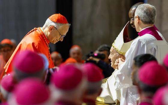Pope Francis hands Cardinal Robert Prevost, prefect of the Dicastery for Bishops, a copy of Spes Non Confundit, ("Hope Does Not Disappoint"), his document proclaiming the Holy Year 2025, during a ceremony in front of the Holy Door of St. Peter's Basilica at the Vatican May 9, 2024. (CNS/Lola Gomez)