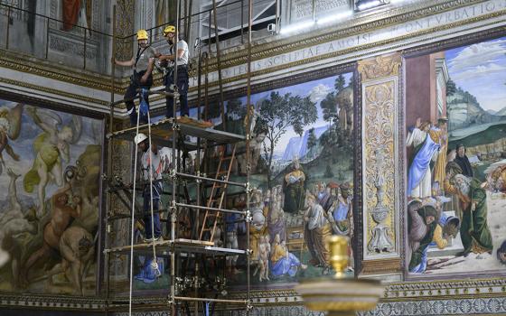 Workers on scaffolding May 2, 2025, attach the stove pipe to the stove that will be used to burn ballots during the conclave to elect a new pope in the Sistine Chapel at the Vatican. Cardinals under the age of 80 will enter the conclave May 7. (CNS/Vatican Media)