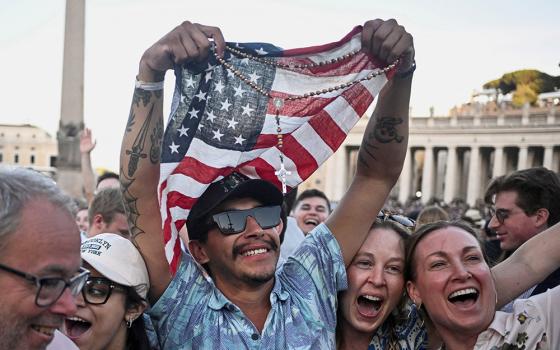 A man holding a rosary and U.S. flag reacts as Cardinal Robert Francis Prevost, who has chosen the papal name Leo XIV, appears on the central balcony of St. Peter's Basilica at the Vatican May 8, 2025, following his election during the conclave. (OSV News/Reuters/Dylan Martinez)