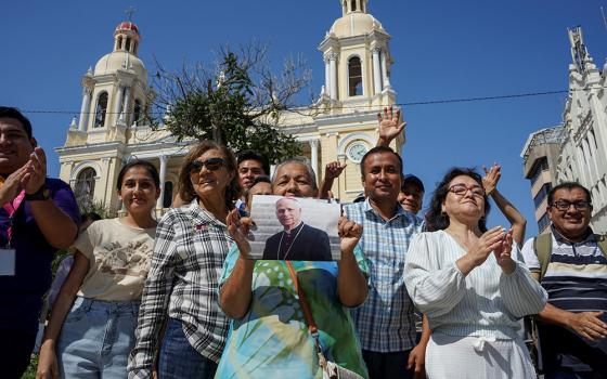 A woman holds an image of then-Cardinal Robert Francis Prevost in front of the Cathedral of St. Mary in Chiclayo, Peru, May 8, 2025, after he was elected the pope at the Vatican and chose the name Leo XIV. As an Augustinian priest, he spent many years as a missionary in Peru. (OSV News/Reuters/Diego Torres Menchola)
