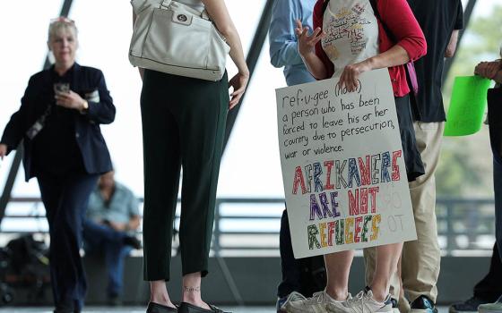 A person holds a sign on the day people from the first group of white South Africans granted refugee status for being deemed victims of racial discrimination under U.S. President Trump's Refugee plan, arrived at Dulles International Airport in Virginia May 12, 2025. (OSV News/Reuters/Kevin Lamarque)