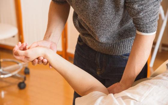 Physical therapist moves patient's arm.