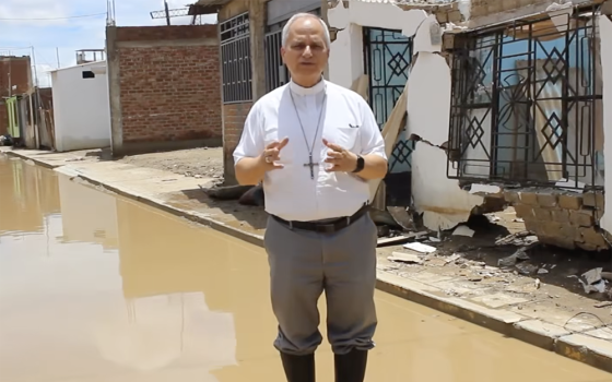 Then-Bishop Robert Prevost, now Pope Leo XIV, stands in floodwaters in the Chiclayo Diocese in the aftermath of heavy rains in northwestern Peru in March 2023, in this screenshot from a video by Caritas Chiclayo (NCR screengrab/Caritas Chiclayo)