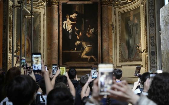 Tourists admire the Pilgrims' Madonna, of Caravaggio is seen at the Basilica of St. Augustine in Rome on May 22, 2025. (AP Photo/Gregorio Borgia)
