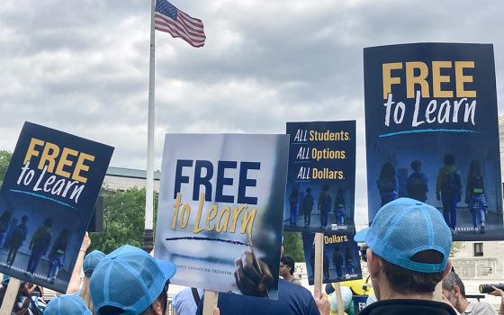 People gathered in front of the U.S. Supreme Court April 30 hold signs supporting that a Catholic charter school, St. Isidore of Seville Catholic Virtual School in Oklahoma, should get state taxpayer support. (NCR photo/Carol Zimmermann)