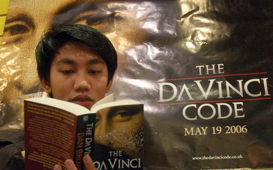 A man reads The Da Vinci Code at a bookstore in Manila, Philippines, on May 13, 2006. The film adaptation was released in 2006. Fr. Andrew Greeley wrote an NCR book review of Dan Brown's novel in 2003. (CNS/Reuters/Joseph Agcaoli) 