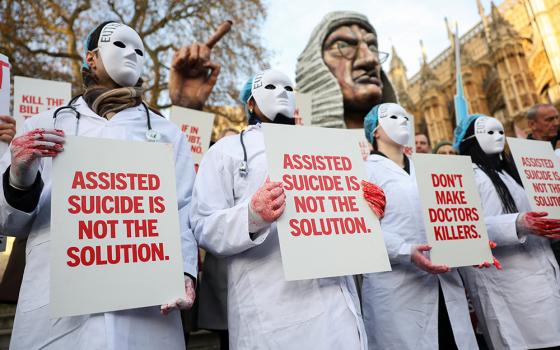 Protesters hold a placard outside Parliament in London as British lawmakers debate an assisted suicide bill on Nov. 29, 2024. (OSV News/Reuters/Mina Kim)