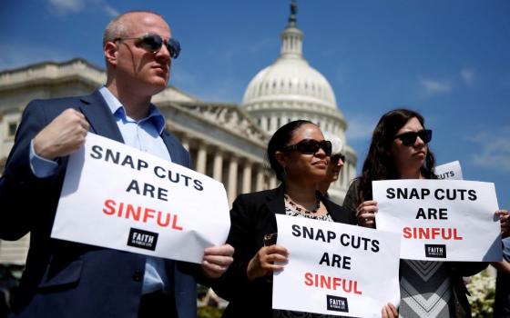  People hold up signs protesting against cuts to the Supplemental Nutrition Assistance Program (SNAP) during a press conference on Capitol Hill in Washington May 7, 2018. (OSV News/Reuters/Joshua Roberts)