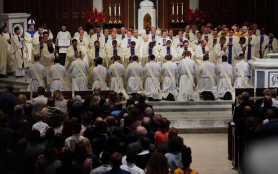 Priests and bishops bless the 12 newly ordained priests during Mass at the Cathedral of St.  Thomas More in Arlington, Va., on June 7. (AP/Jessie Wardarski)
