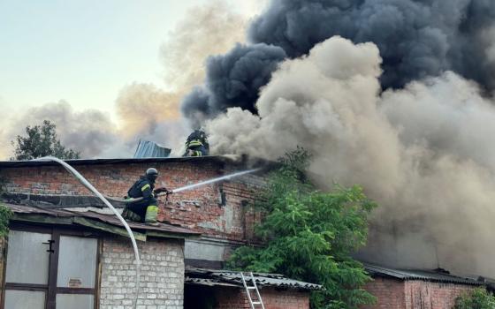 Firefighters work amid smoke from drone attack.