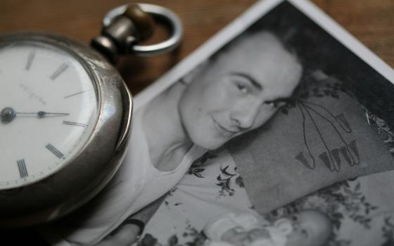 A pocket watch next to an old photograph of a father and child (Unsplash/Anne Nygard)