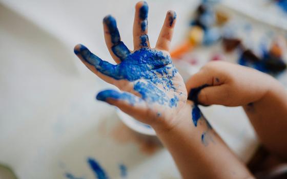 A child's hand with blue paint (Unsplash/Phil Hearing)