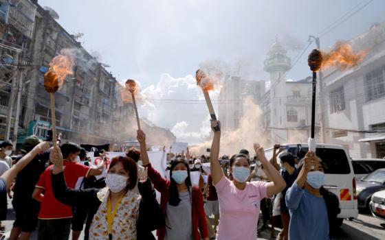 A group of women hold torches as they protest against the military coup in Yangon, Myanmar, July 14, 2021. People from all walks of life in Myanmar observed a "silent strike" in defiance of the ruling junta Feb. 1, 2022, the anniversary of the military coup. (CNS photo/Reuters)
