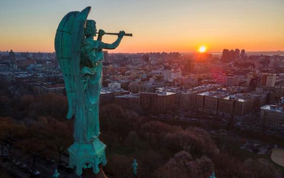 A bronze statue of the archangel Gabriel blowing a trumpet stands atop the Cathedral of St. John the Divine as the sun rises in the Morningside Heights neighborhood of the borough of Manhattan in New York  March 26, 2023. (RNS/AP/Ted Shaffrey, File)